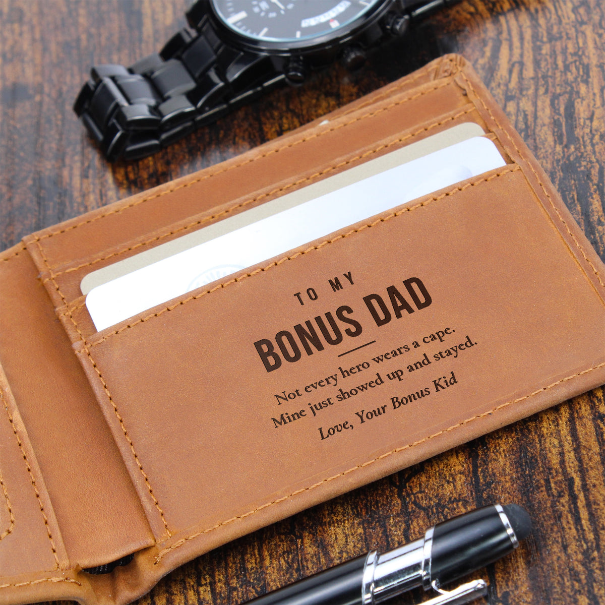 Close-up of brown engraved leather wallet with To My Bonus Dad message beside a watch