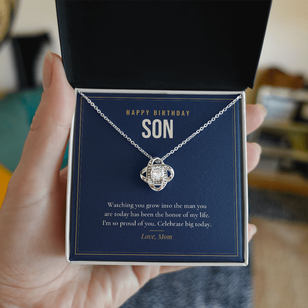 Hand holding open gift box with 14K white gold finish Birthday Love Knot necklace for Son and "Happy Birthday Son" message card