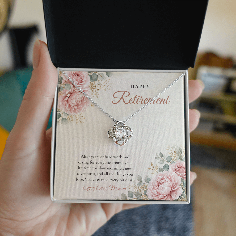 Hand holding open gift box with 14K white gold finish Retirement Love Knot necklace for Her and "Happy Retirement" message card