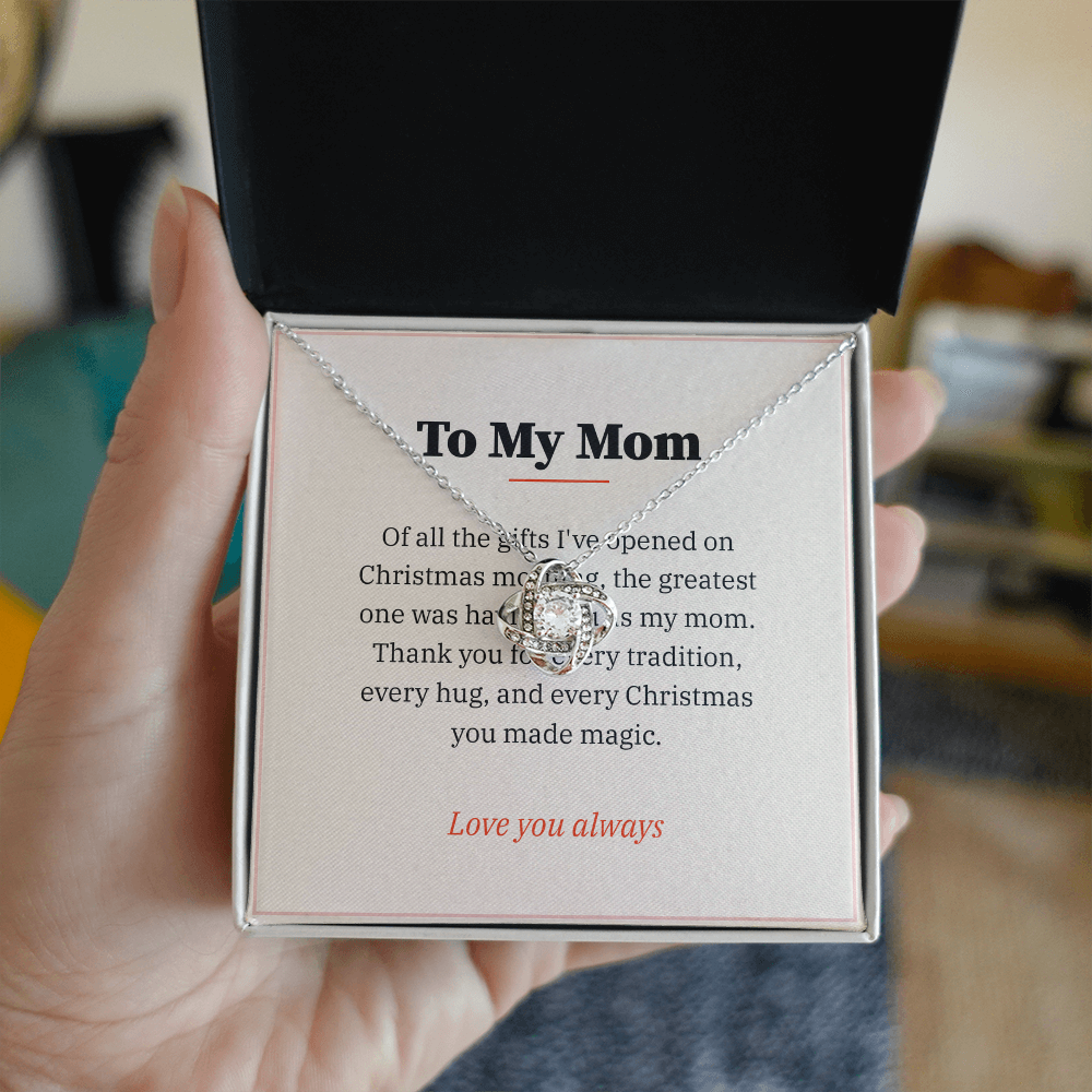 Hand holding gift box with silver Love Knot necklace and To My Mom Christmas message card
