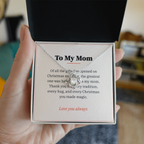 Hand holding gift box with silver Love Knot necklace and To My Mom Christmas message card