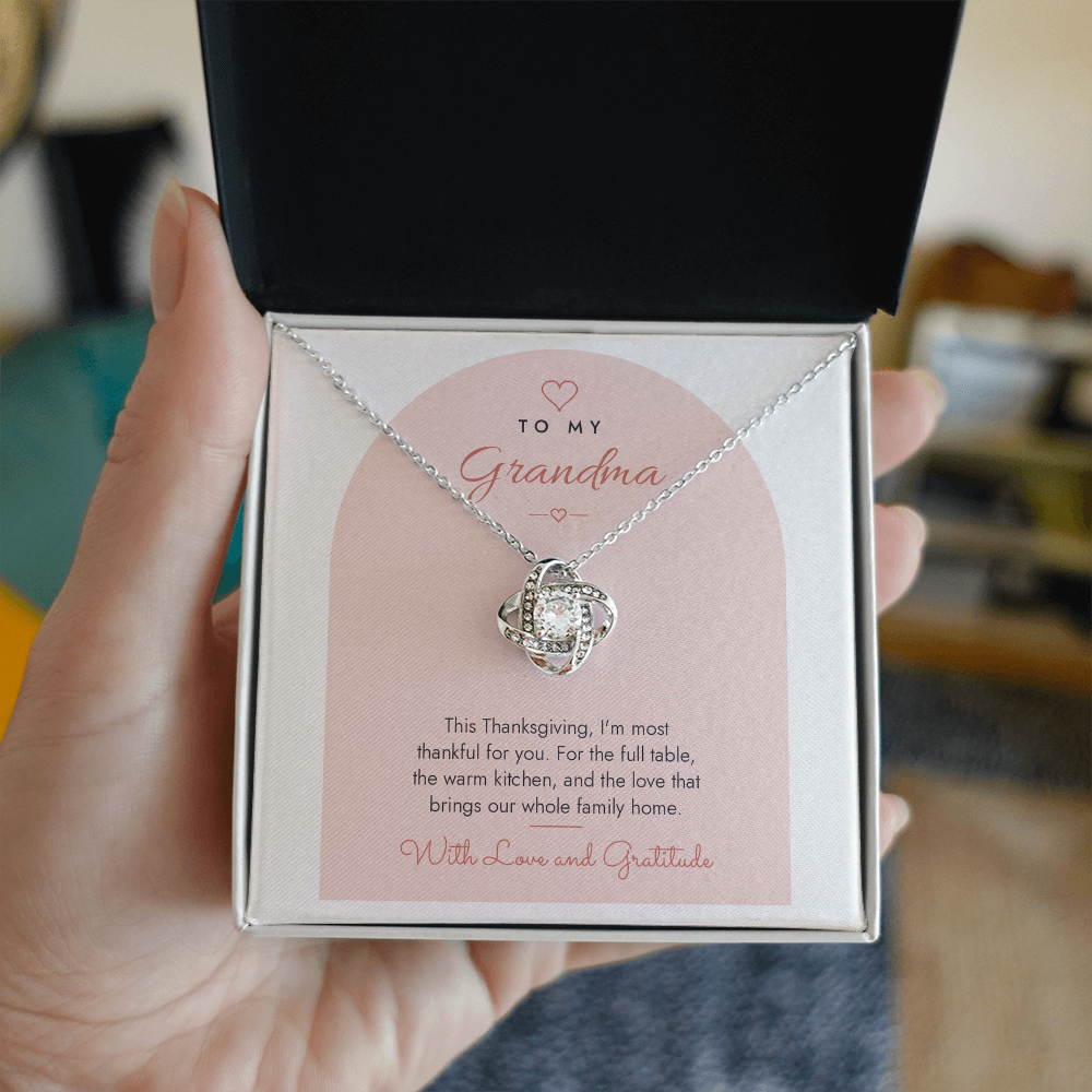 Hand holding open gift box with silver finish Love Knot necklace for Grandma and modern message card
