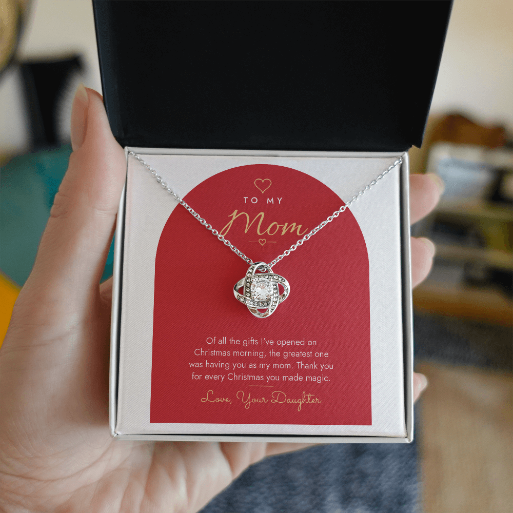 Hand holding open gift box with silver finish Love Knot necklace for Mom from Daughter and modern message card