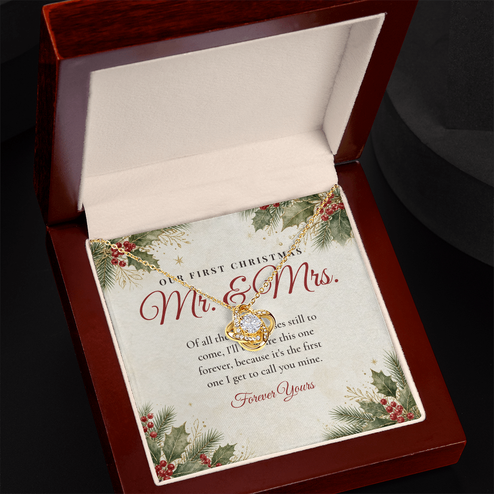 Yellow gold Love Knot necklace for wife and Our First Christmas Mr. & Mrs. message card in open mahogany luxury box on dark background