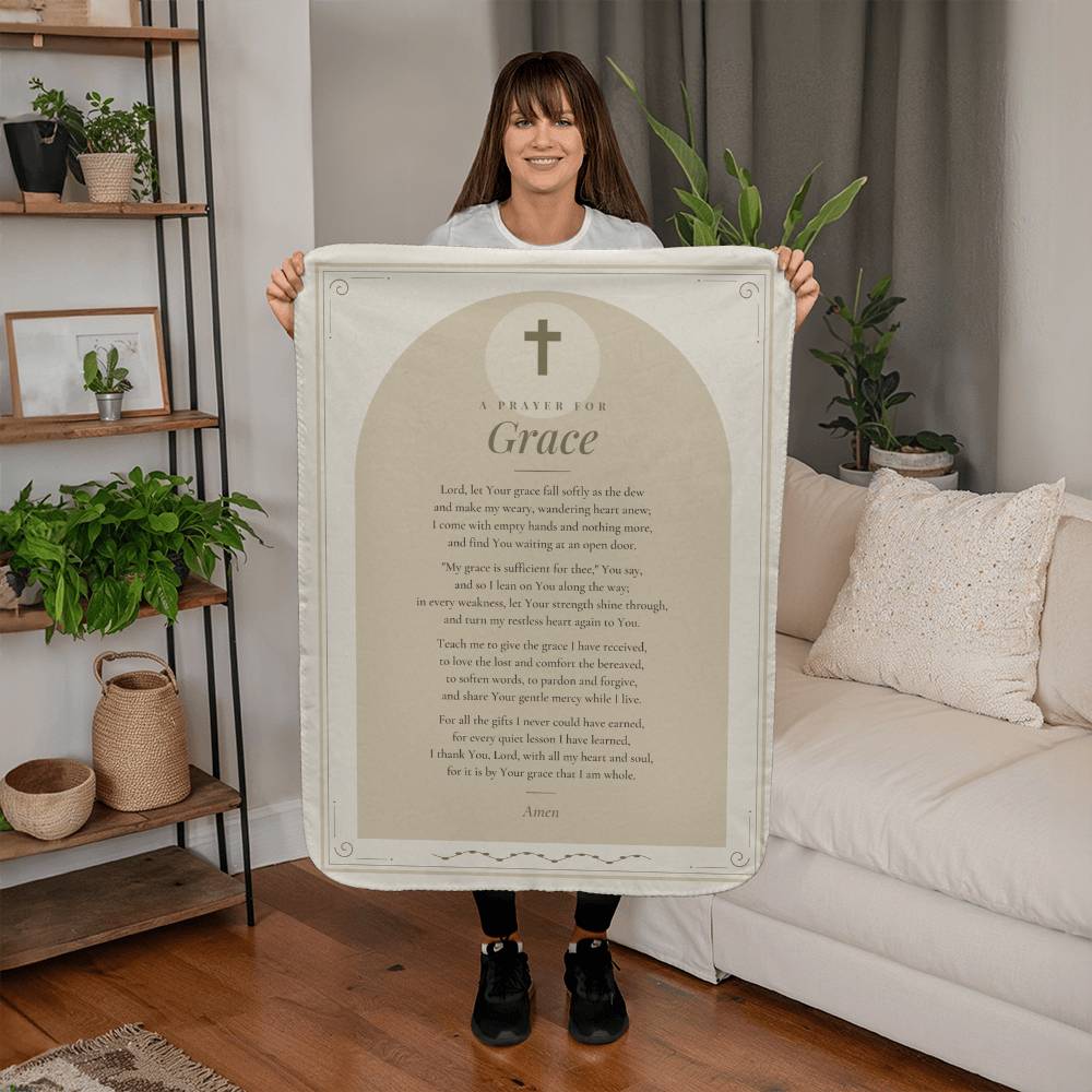 Woman holding a tan grace prayer blanket with printed prayer in a living room