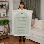 Woman holding a sage green prayer blanket for daughter with printed prayer in a living room