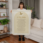 Woman holding a cream baby prayer blanket with printed prayer in a living room