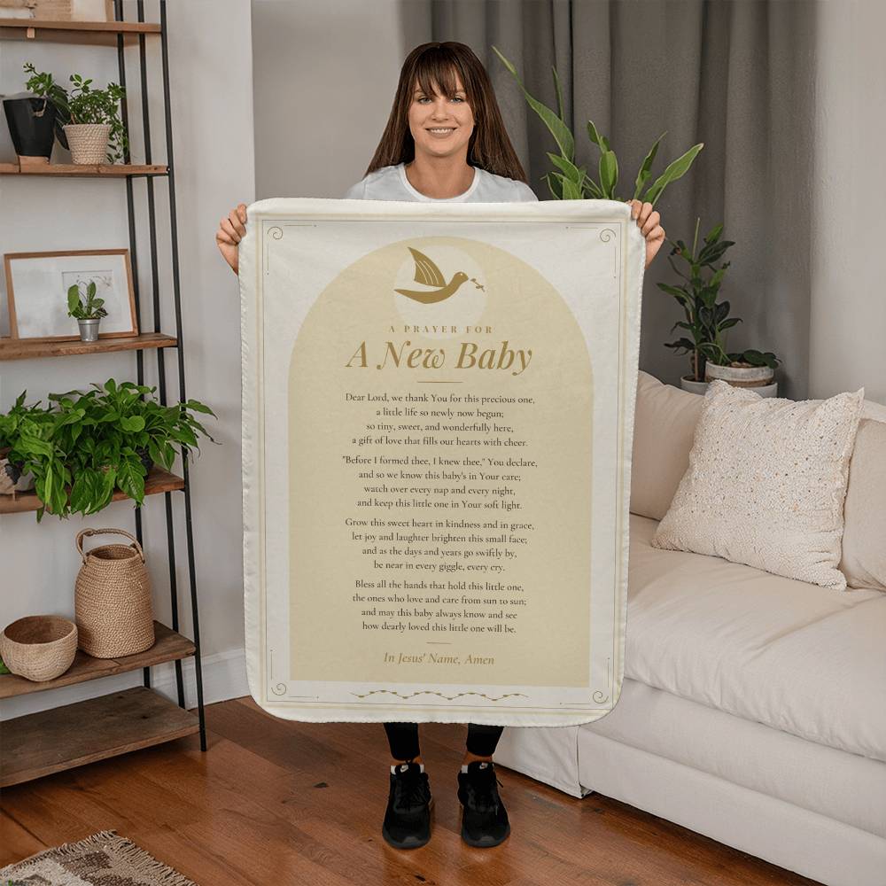 Woman holding a cream baby prayer blanket with printed prayer in a living room