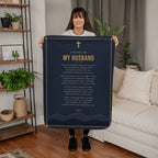 Woman holding a navy blue prayer blanket for husband with printed prayer in a living room