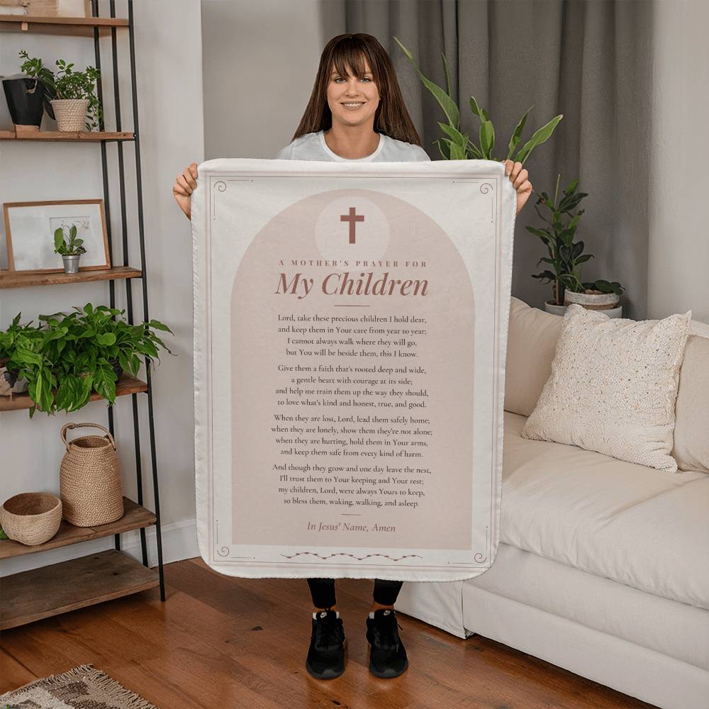 Woman holding a blush mothers prayer blanket with printed prayer in a living room