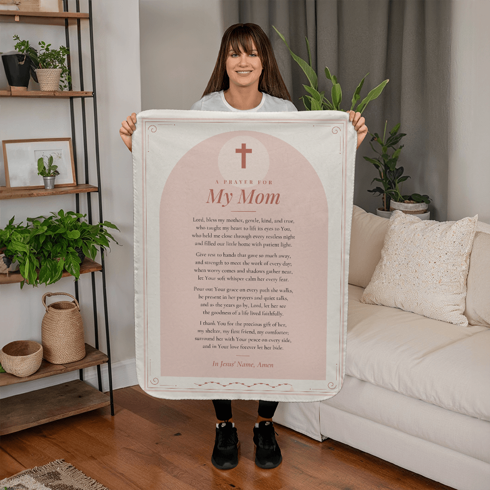 Woman holding a soft pink prayer blanket for mom with printed prayer in a living room