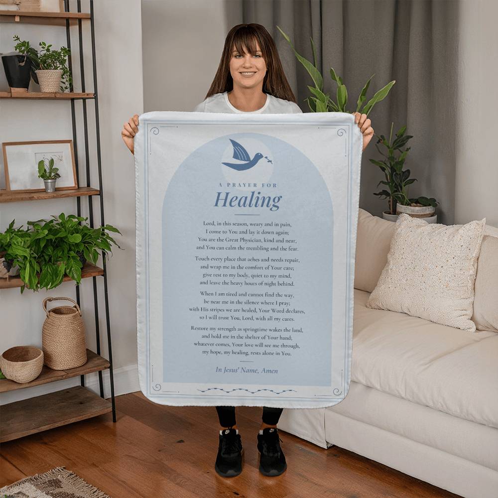 Woman holding a light blue healing prayer blanket with printed prayer in a living room