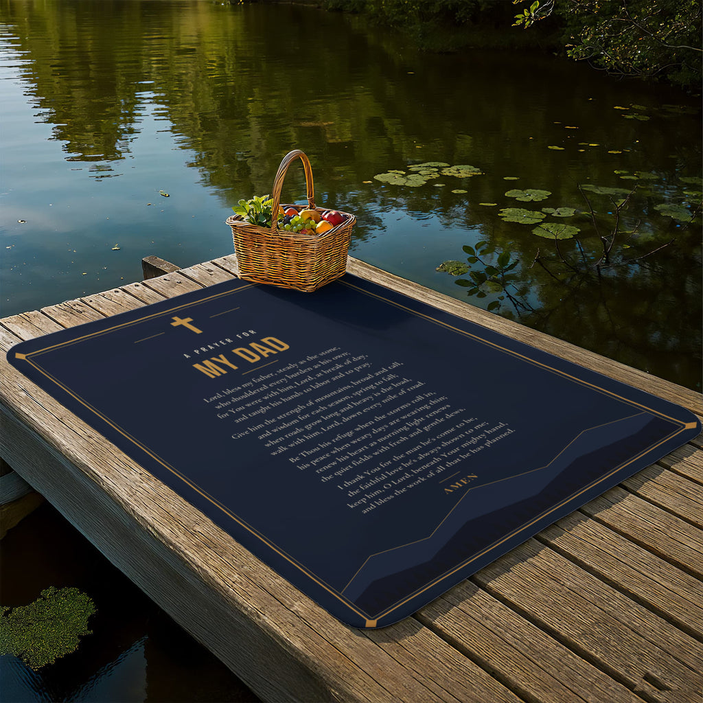 Navy blue prayer blanket for dad laid out on a lakeside dock with picnic basket