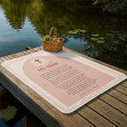 Soft pink prayer blanket for mom laid out on a lakeside dock with picnic basket