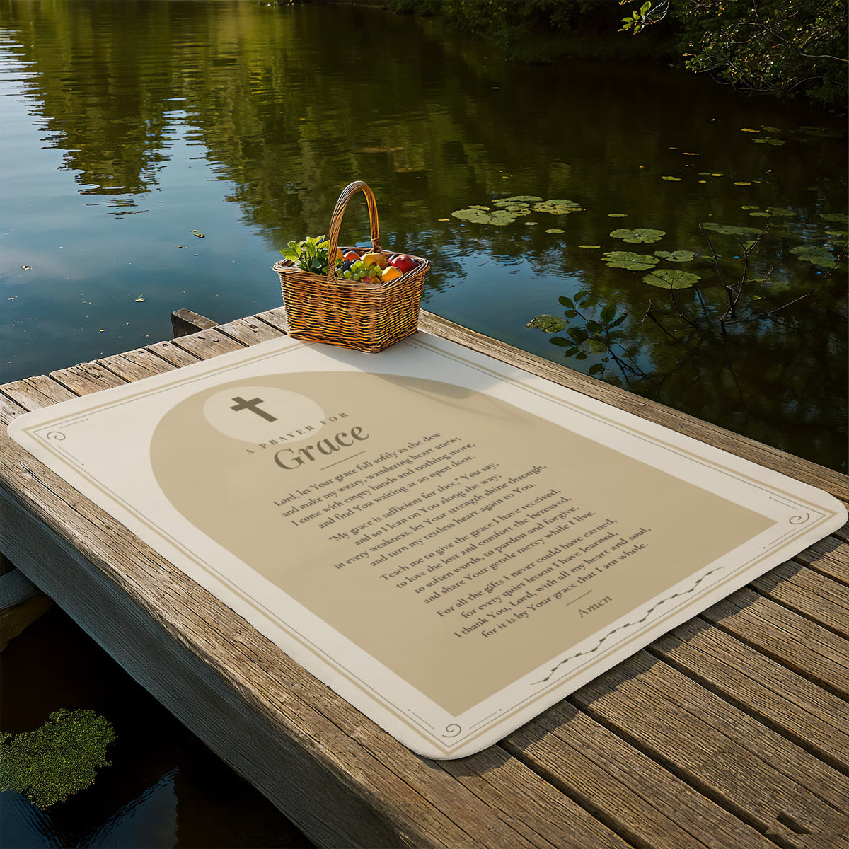 Tan grace prayer blanket laid out on a lakeside dock with picnic basket