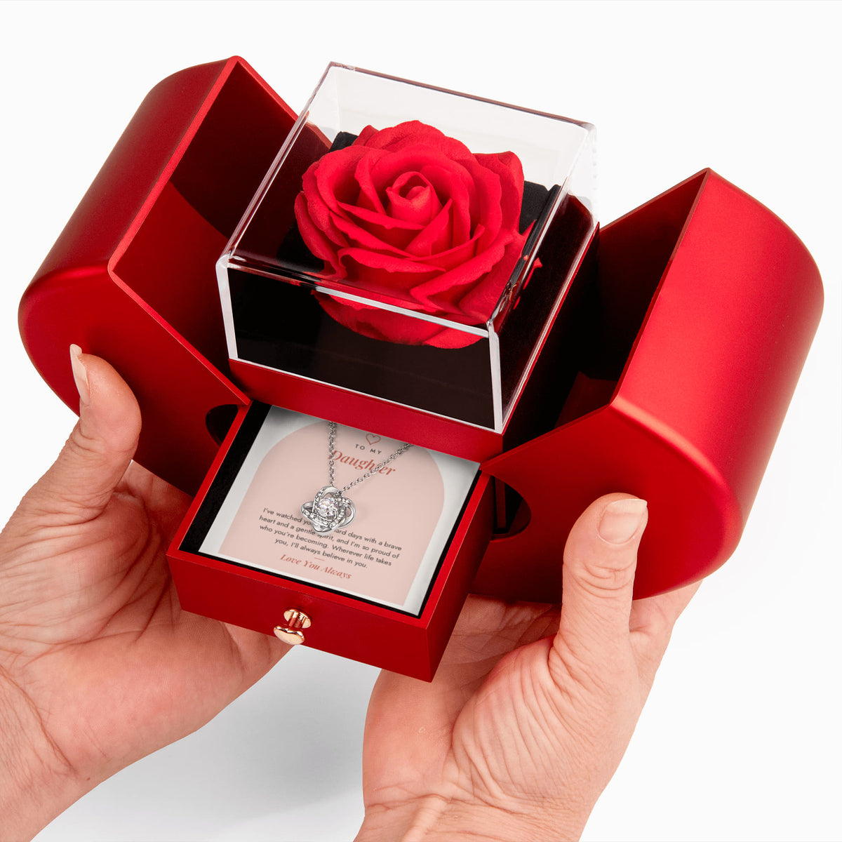 Hands opening red rose box showing Brave Heart Love Knot necklace for Daughter